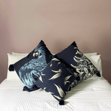 Load image into Gallery viewer, printed eucalyptus gumleaf on blue square linen designer cushion with tassels and handmade in Australia on a white bed in a room with terracotta walls
