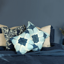 Load image into Gallery viewer, several printed indigo blue shibori square linen cushions on a blue bed in a dark blue room