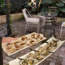 Load image into Gallery viewer, Picture of seafood platters on their way to a garden table in the evening
