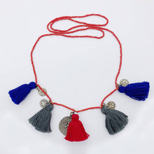Load image into Gallery viewer, Ethically sourced Old Fashioned Online multi coloured red beaded necklace with blu, grey and red tassels and five silver amulet charms on flat lay
