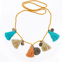 Load image into Gallery viewer, Ethically sourced Old Fashioned Online orange beaded necklace with beige and orange and turquoise tassels and five silver amulet charms on flat lay
