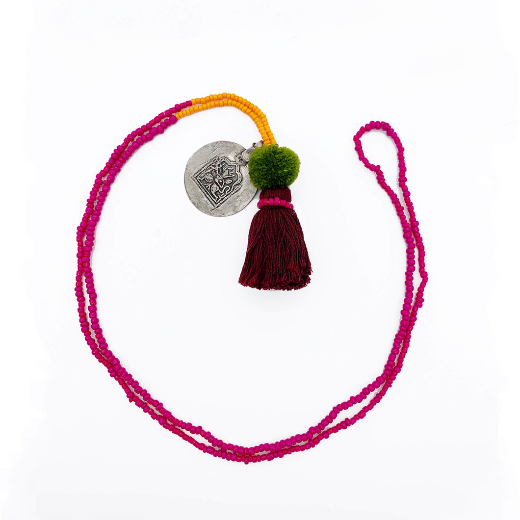 Colorful Old Fashioned Online beads with tassel, pompom and silver amulet charm necklace in pink and blue on flat lay