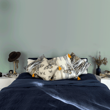 Load image into Gallery viewer, soft paperbark and butterflies in grey yellow and beige neutrals printed on square linen designer cushions on a navy blue linen bed in a bedroom with sage walls
