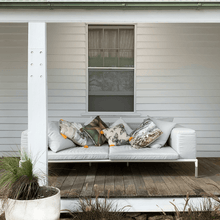Load image into Gallery viewer, soft paperbark and butterflies in grey, yellow and beige neutrals printed on square linen designer cushions on a lounge on the veranda of a victorian farm house
