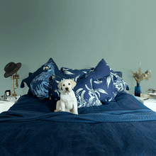 Load image into Gallery viewer, Guide dog puppy in blue bed  with black cockatoo printed on indigo square linen designer cushion with tassels handmade in Australia
