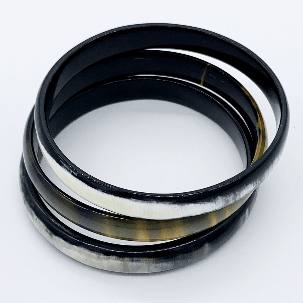 A picture of a stack of 6 slender monochrome Old Fashioned Online bangle bracelet, ethically sourced natural buffalo horn